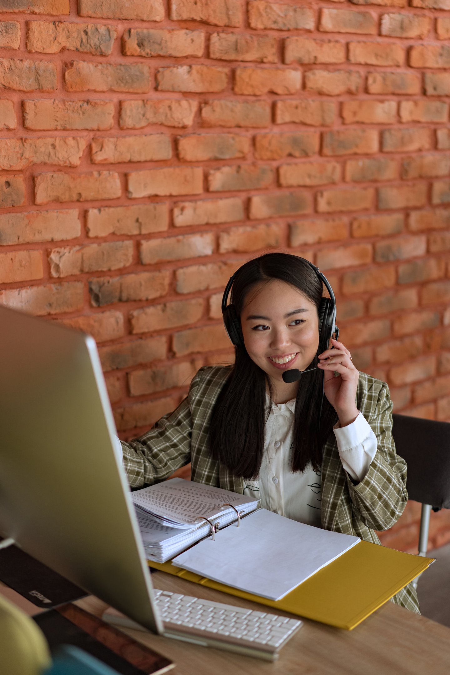 a woman in a plaid shirt and headphones on a laptop