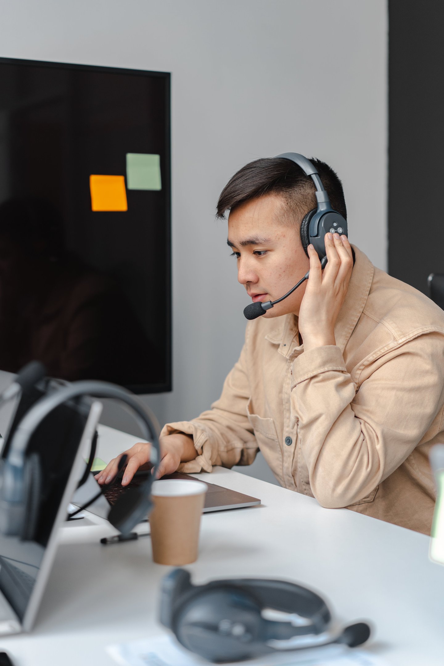 a man in a tan jacket and headphones on a laptop